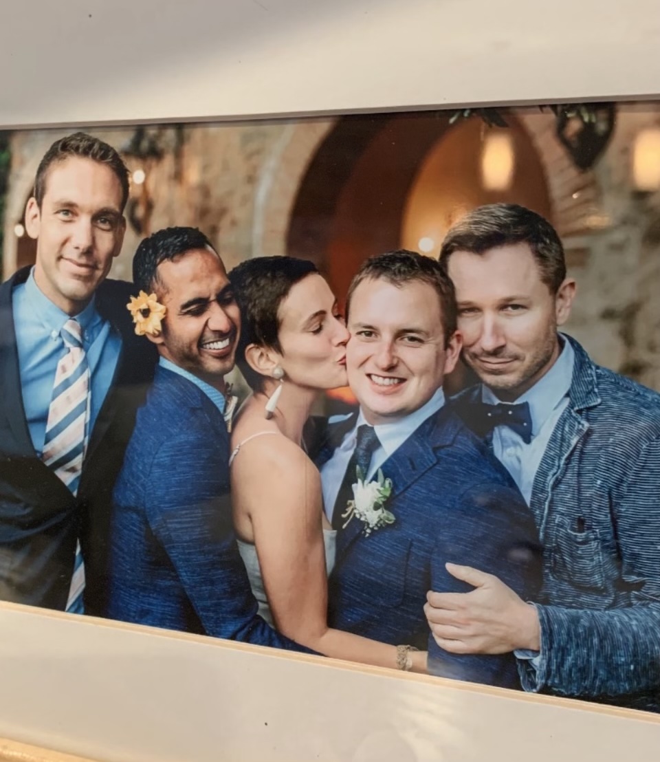 Elliot with friends at a wedding, the bride kissing the groom