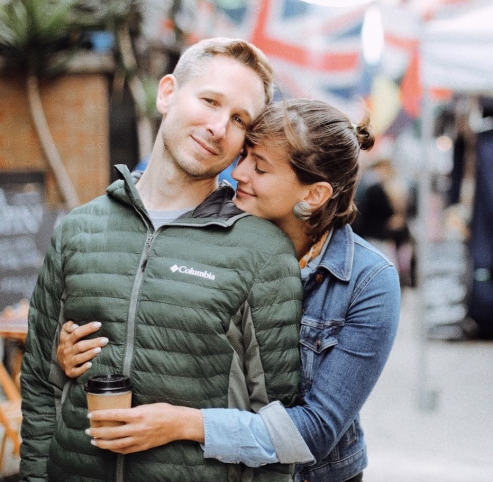 Elliot with a friend resting her head on his shoulder at a market