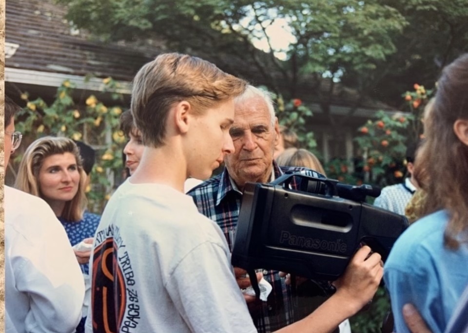 A young Elliot holding a video camera at a family gathering